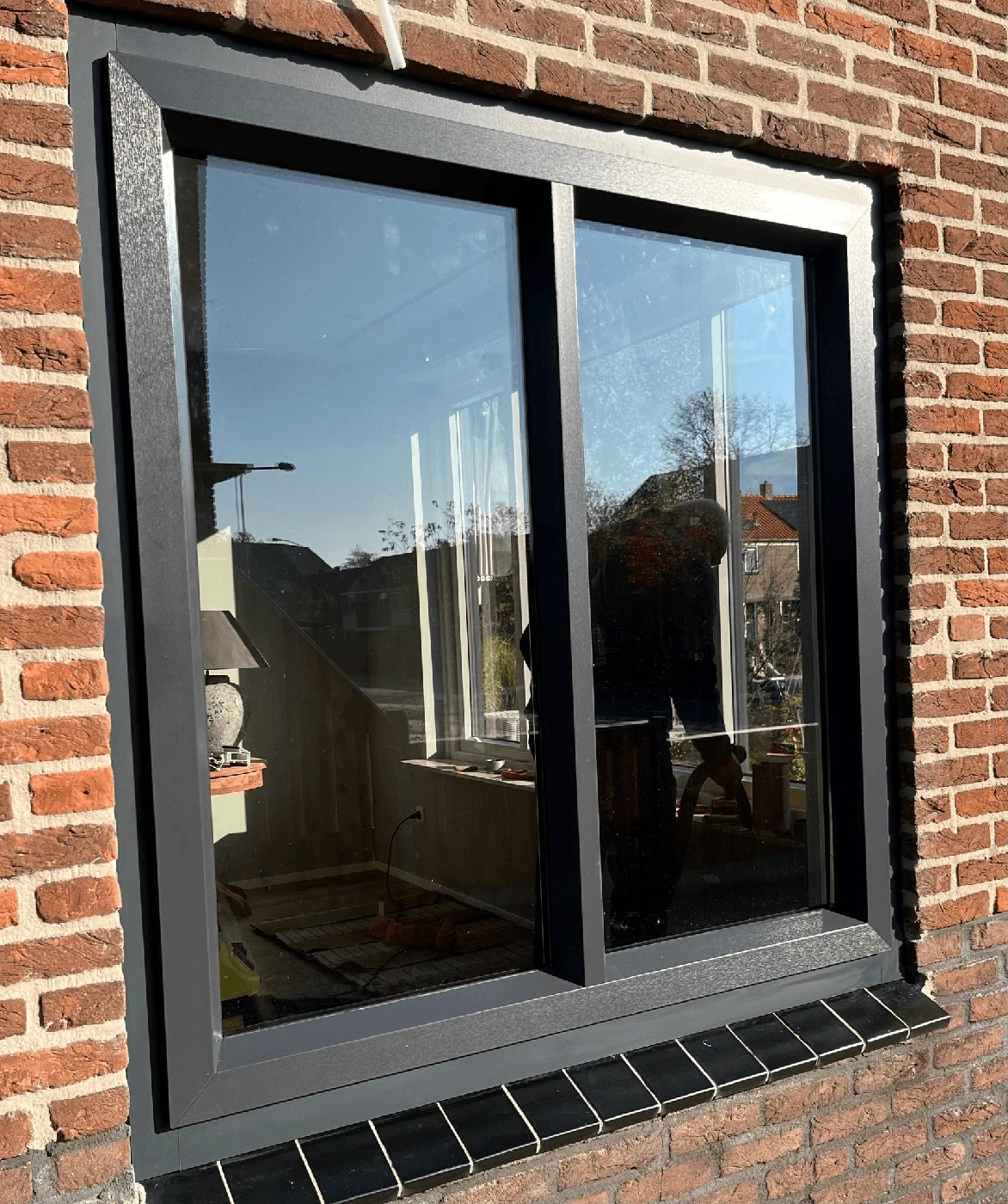 Donkere kozijnen in bakstenen gevel